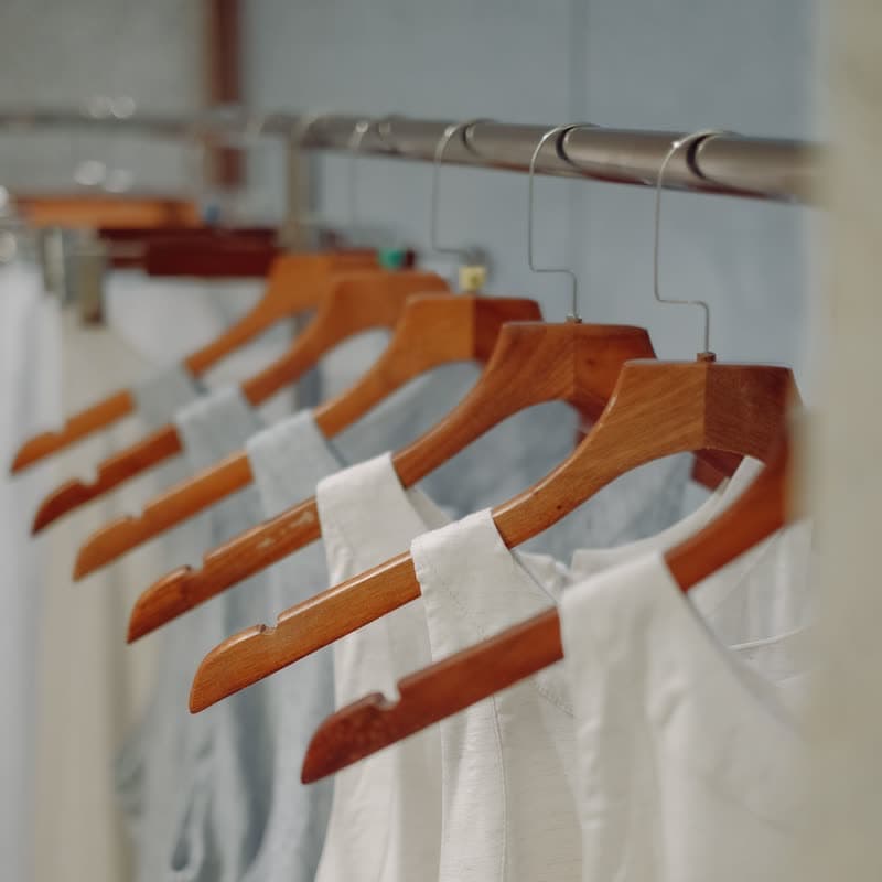 Linen tops on wooden hangers along a clothes rail