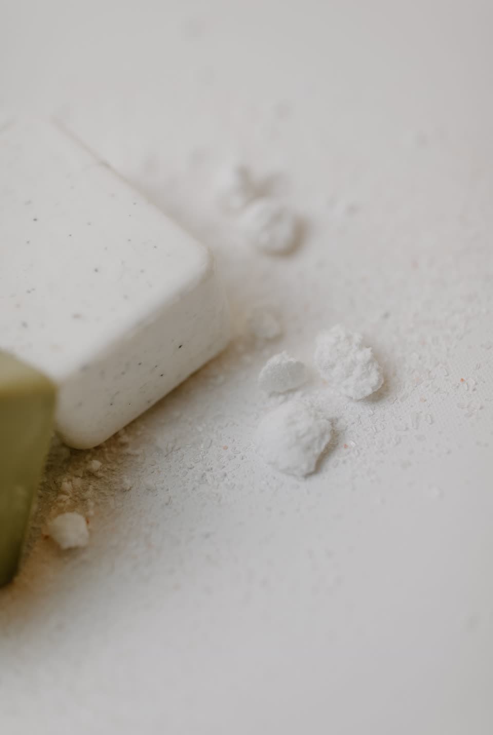 A detergent tablet crumbling on a white surface